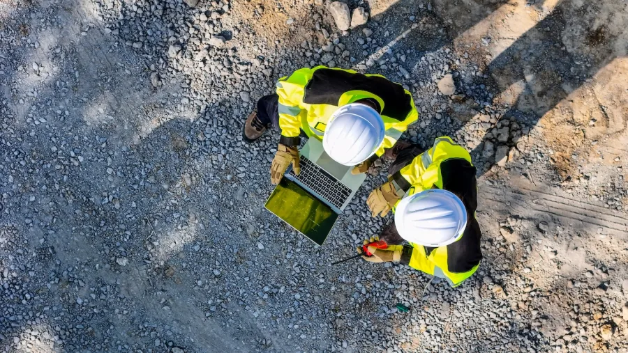 Two crew members in hi-vis training over a laptop on site