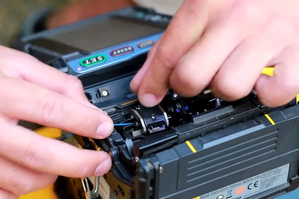 Technician fusing fiber strands in a splicing machine